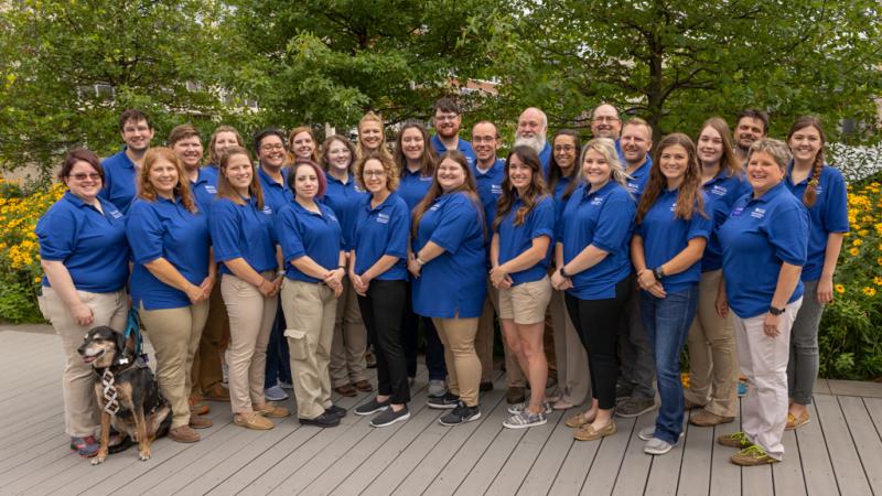 CASE attendees group photograph all dressed in wildcat blue shirts in the deck, garden area outside of the Garrigus Building