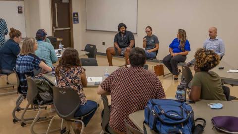 A group of students sit in a circle and discuss topics