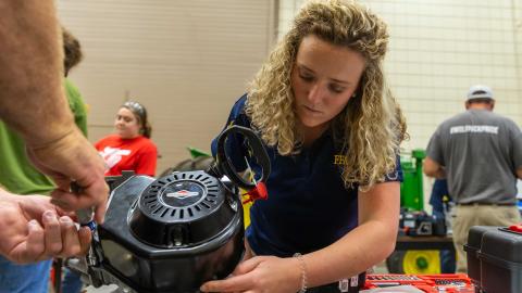 A student works on a small gas engine in a lab