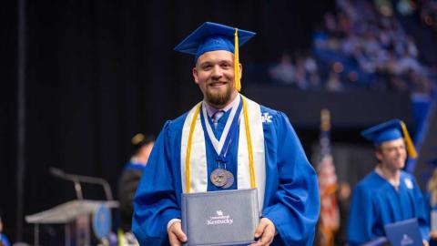 A student holds his degree at commencement