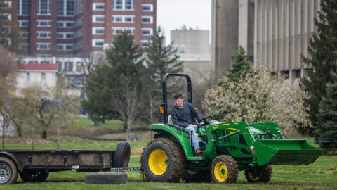 A student drives a tractor in front of the Gluck building during a UK Field Day competition